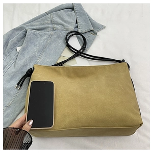 Sac bandoulière en daim jaune moutarde avec bandoulière tressée noire et un téléphone