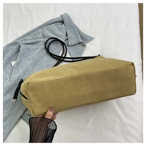 Détail du sac bandoulière en daim kaki avec cordon noir sur veste en jean décontractée