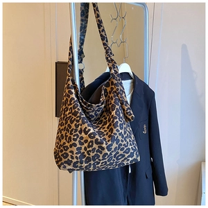 Detail of large leopard print canvas tote bag styled with a black blazer on a hanger
