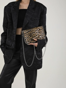 Detail of leopard print crossbody bag with silver crystal trim on a black fashion outfit