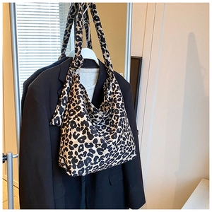Detailed view of leopard print canvas tote bag hanging on a rack with a black blazer