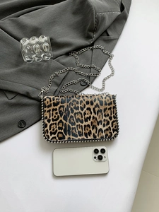 Detailed view of leopard print crossbody bag with silver chain strap and metallic bead trim