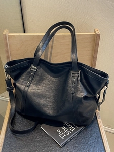 Large black vintage tote bag with star rivets on a wooden chair, urban casual style
