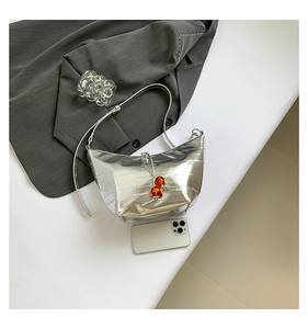 Detalle del bolso plateado con textura de cocodrilo, cuentas naranjas y una correa delgada