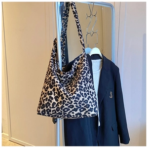 Close-up of leopard print canvas tote bag hanging on a rack with a casual fashion outfit