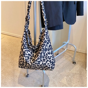 Detail of trendy leopard print canvas hobo bag featuring a decorative knotted shoulder strap