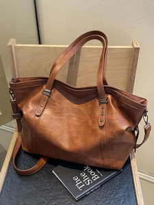Retro brown leather tote bag with star rivets on a wooden chair for daily commute