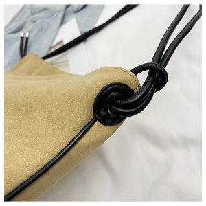 Détail du sac bandoulière en daim kaki avec bandoulière en cuir noir nouée