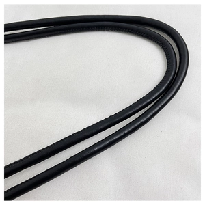 Détail de la bandoulière en cuir noir avec coutures précises sur un sac bandoulière en toile