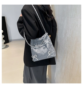 Dettaglio borsa a secchiello in tessuto grigio con fiocchi 3D argento e tracolla a catena