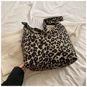 Close-up of leopard print canvas tote bag with wide shoulder strap on fabric background