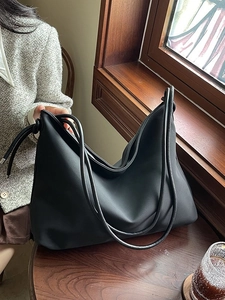 Grand sac hobo en cuir PU noir avec fines anses doubles sur une table de café en bois