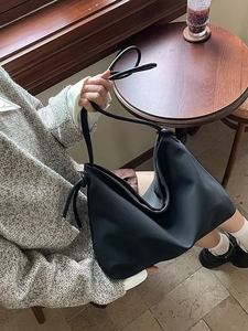 Sac fourre-tout minimaliste en nylon noir avec nœuds coulissants sur une table