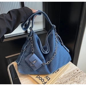 Gros plan d'un sac hobo en jean bleu avec chaîne argentée et petit pochon assorti