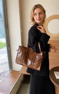 Détail d'un cabas en cuir marron avec nœud décoratif latéral et double poignée