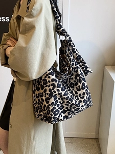 Stylish large leopard print canvas tote bag with knot strap worn by model in trench coat