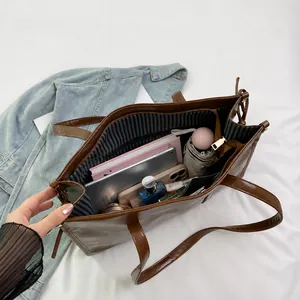 Détail de la grande capacité et de la doublure rayée de ce sac cabas marron avec objets