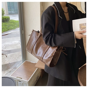Detail der braunen Vintage PU-Leder Tragetasche mit eleganter seitlicher Schleifenverzierung