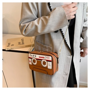 Macro detail of brown cassette tape clutch bag with dual zippers and gold chain strap