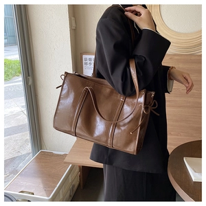 Detail der braunen Vintage PU-Leder-Einkaufstasche mit seitlicher Schleife und Tragegurt