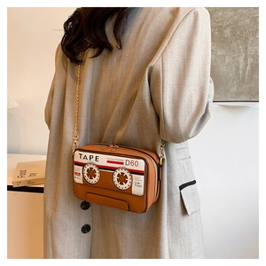 Macro view of vintage brown cassette tape crossbody bag with metal chain detail