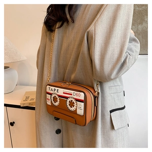 Detail of vintage cassette tape crossbody bag in brown PU leather with gold chain strap