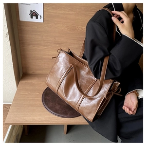 Detail einer großen braunen Shopper-Tasche aus geöltem Leder mit dekorativer Schleife