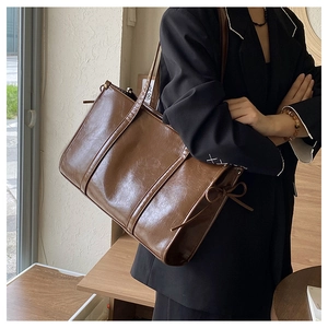 Detailansicht der braunen Vintage Leder-Tasche mit seitlichem Schleifen-Kordelzug am Model