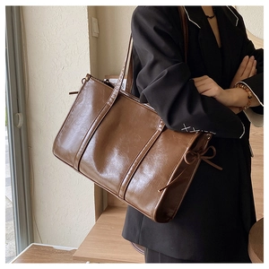 Detailaufnahme der dunkelbraunen Vintage-Einkaufstasche aus Leder mit stilvoller Schleife