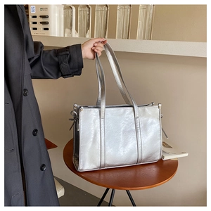 Detailansicht der silbernen Metallic-Tasche mit eleganten Schleifen-Akzenten und Lederriemen