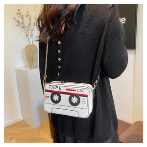 Chic white cassette-shaped crossbody bag with gold chain strap shown on a model