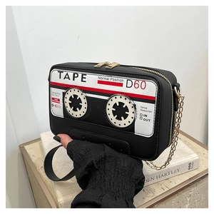 Detail view of the black leather cassette tape shaped bag with gold chain and dual zippers