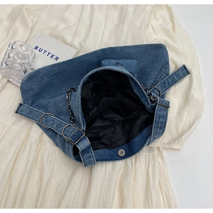 Detail of blue denim tote bag showing magnetic snap closure and internal zipper pocket