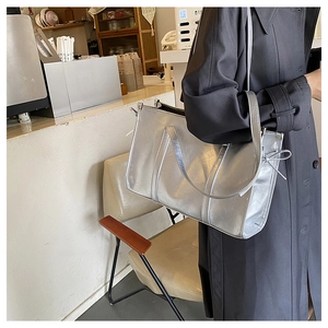 Detail einer silbernen Metallic-Tote-Bag mit seitlicher Schleife und Doppelriemen