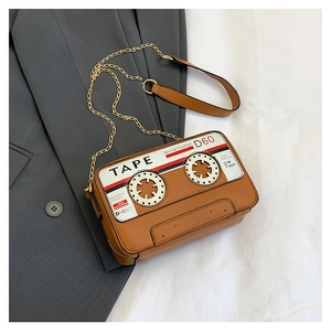 Detail of retro cassette tape crossbody bag with gold chain strap on grey blazer