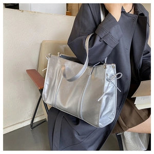 Detail der silbernen Metallic-Tote-Bag mit seitlicher Schleifendekoration und Glattleder
