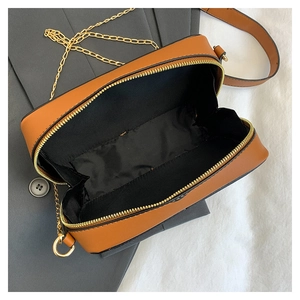 Top view of brown cassette cross-body bag showing golden zipper and black fabric lining