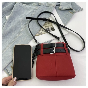 Dettaglio della piccola borsa a secchiello rossa con coulisse accanto a uno smartphone per misura