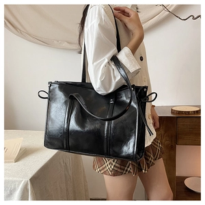 Detail der schwarzen Shopper-Tasche mit Öl-Wachs-Finish und Schleife am Modell