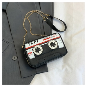 Detail of vintage cassette tape crossbody bag with gold chain strap on grey blazer