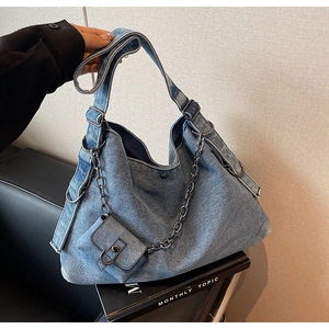 Détail du sac hobo en denim bleu vintage avec chaîne en métal et petite pochette amovible