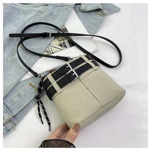 Dettaglio borsa a secchiello beige con cinturini neri e coulisse su sfondo denim