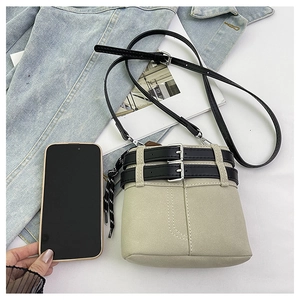 Dettaglio di una borsa a secchiello beige opaca con cinturini neri e nodi di corda