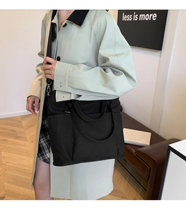 Black canvas tote bag with adjustable shoulder strap shown on model for daily commuting