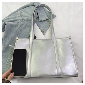 Detail-Größenvergleich einer silbernen Metallic-Tote-Bag neben einem Smartphone-Gerät