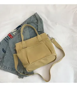Detail view of the beige canvas tote bag showing multiple front pockets and thick straps