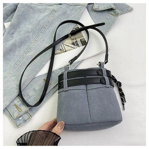 Dettaglio della mini borsa a secchiello blu satinata con cintura in pelle e lacci