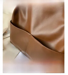 Close-up detail of the brown leather tote bag showing external pocket with neat stitching
