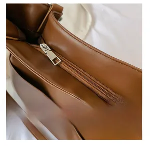 Close-up of the smooth metal zipper and premium leather texture on the brown tote bag