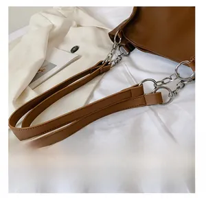Detail of brown leather and silver metal chain strap on minimalist tote bag